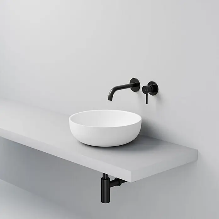 Vola Waschtisch - 0 x 0 cm - Weißes rundes Aufsatzwaschbecken mit schwarzer Wandarmatur und Griff, sowie schwarzem Abflussrohr.