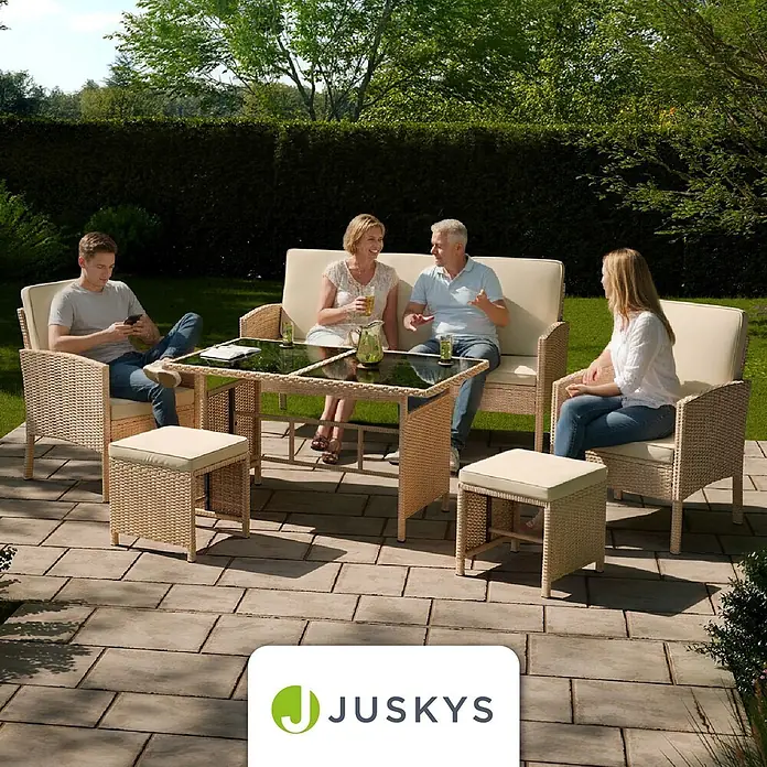 Juskys Loungemöbel-Set Turin - 6 -tlg., Geflecht: Polyrattan; Tischplatte: Gehärtetes Glas; Gestell: Stahl; Bezüge: 100 % Polyester; Polster: 80 % Schaumstoff, 20 % Weichfasern, Creme - Helles beiges Rattan-Gartenmöbelset mit cremefarbenen Kissen: Sofa, Sessel, Tisch und Hocker, auf einer Gartenterrasse genutzt.