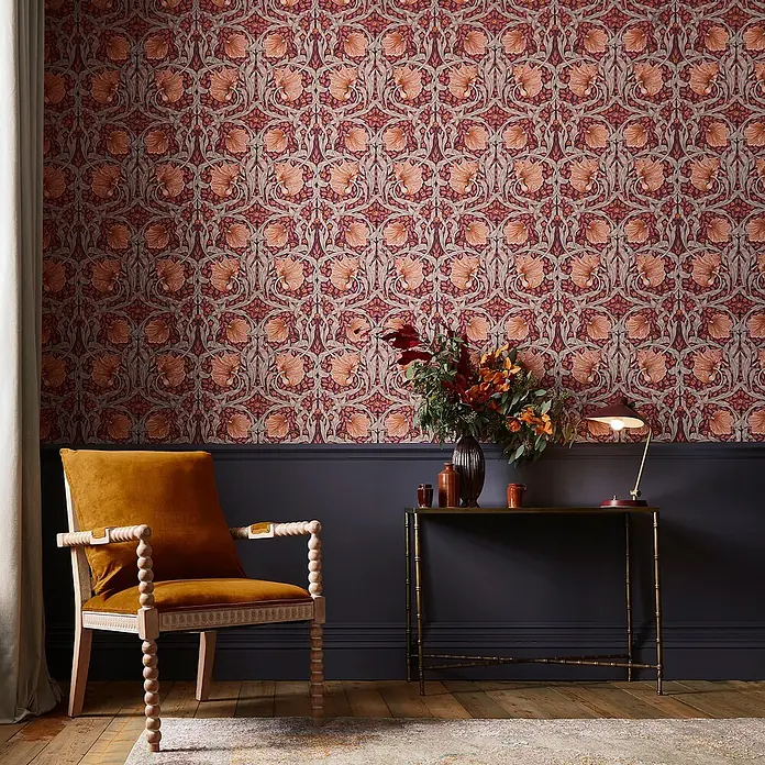 William Morris At Home Vliestapete Pimpernel Blumen - Lila, Floral, 1.000 x 52 cm - Tapete mit kunstvollem botanischem Muster in Terrakotta, Burgund und Salbeigrün, über dunkler Wandvertäfelung in einem Wohnraum.