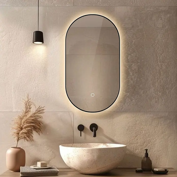 Lumoire Lichtspiegel ONYX -  - Ovaler beleuchteter Spiegel mit schwarzem Rahmen und warmer Hintergrundbeleuchtung, über einem Waschbecken im modernen Bad.