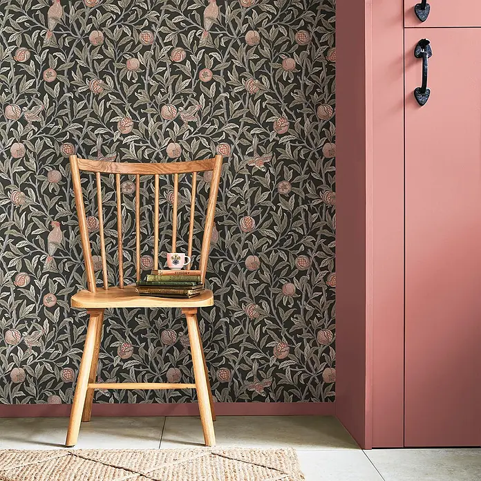 William Morris At Home Vliestapete Vogel & Granatapfel - Grau, Floral, 1.000 x 52 cm - Dunkle botanische Tapete mit Blättern, Früchten und Vögeln, passend zu einem rosa Schrank und Holzstuhl.