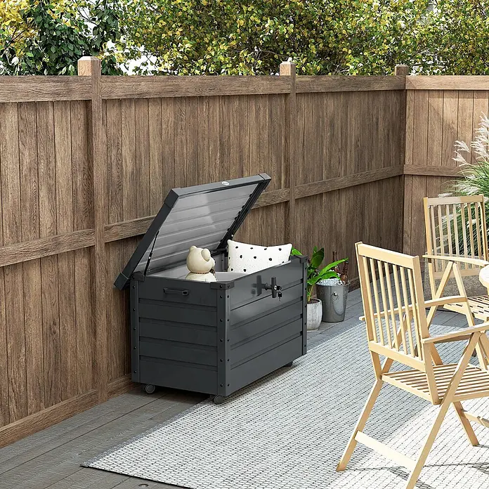 Furnicato Garten-Aufbewahrungsbox - Dunkelgrau, Stahl - Dunkelgraue Outdoor-Aufbewahrungsbox mit offenem Deckel, Teddybär und Kissen auf einer Terrasse neben einem Holzzaun.