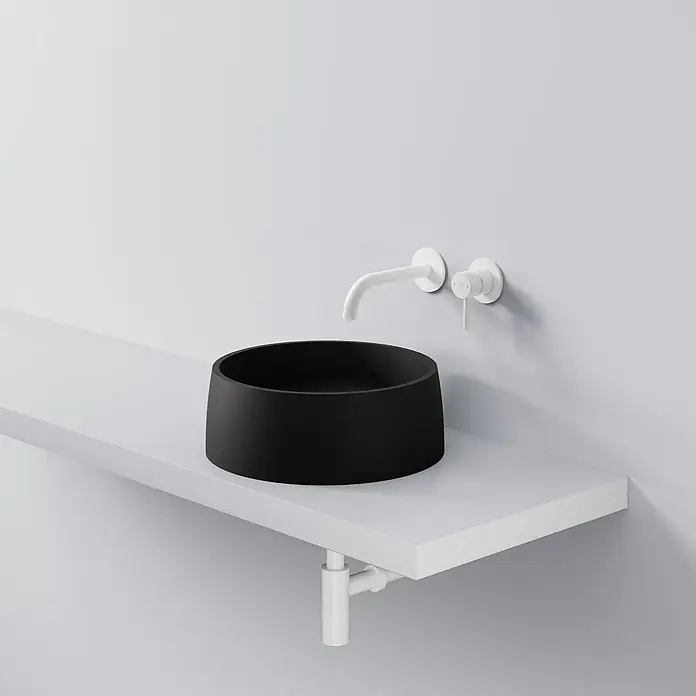 Vola Waschtisch - 0 x 0 cm - Schwarzes rundes Aufsatzwaschbecken mit weißer Wandarmatur auf einem weißen schwebenden Regal.