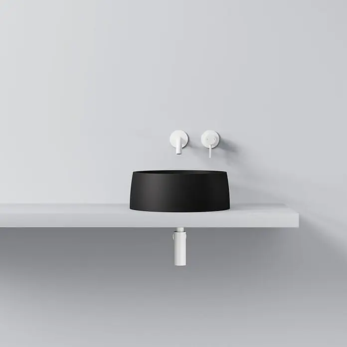 Vola Waschtisch - 0 x 0 cm - Schwarzes zylindrisches Aufsatzwaschbecken mit weißen Wandarmaturen und weißem Ablaufrohr auf einem weißen Regal.