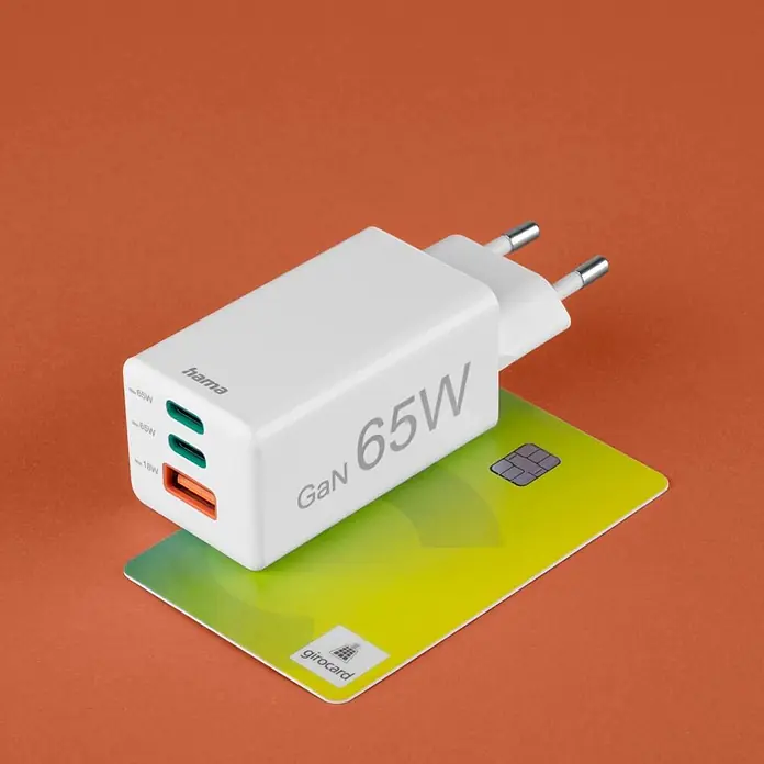 Hama Schnellladegerät 00201996 GaN 2x USB-C 1x USB-A Mini PD 65 W - Weiß - Weißes Hama GaN 65W Ladegerät mit zwei USB-C- und einem USB-A-Anschluss, auf einer grünen girocard.