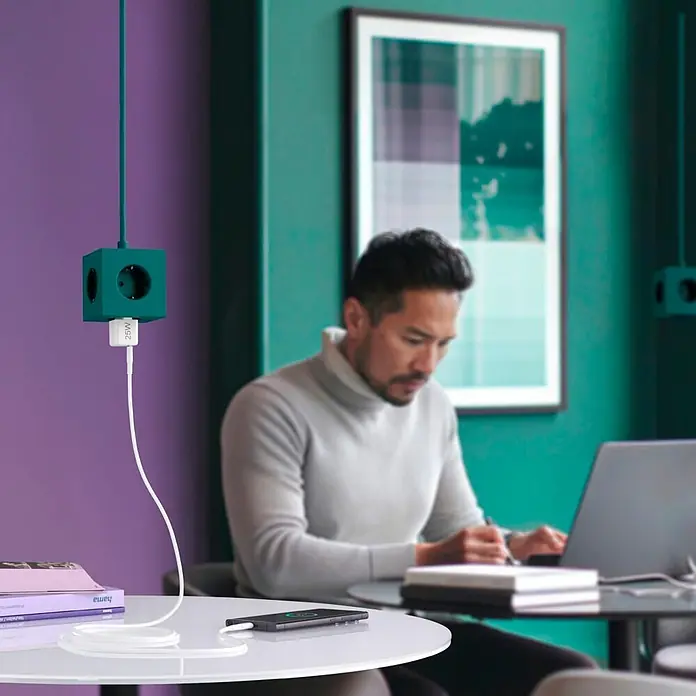 Hama Schnellladegerät 00201981 USB-C Super-Mini-Charger PD 25 W - Weiß - Türkise, würfelförmige Steckdosenleiste hängt von der Decke, mit weißem 25W USB-Ladegerät, das ein Smartphone lädt.