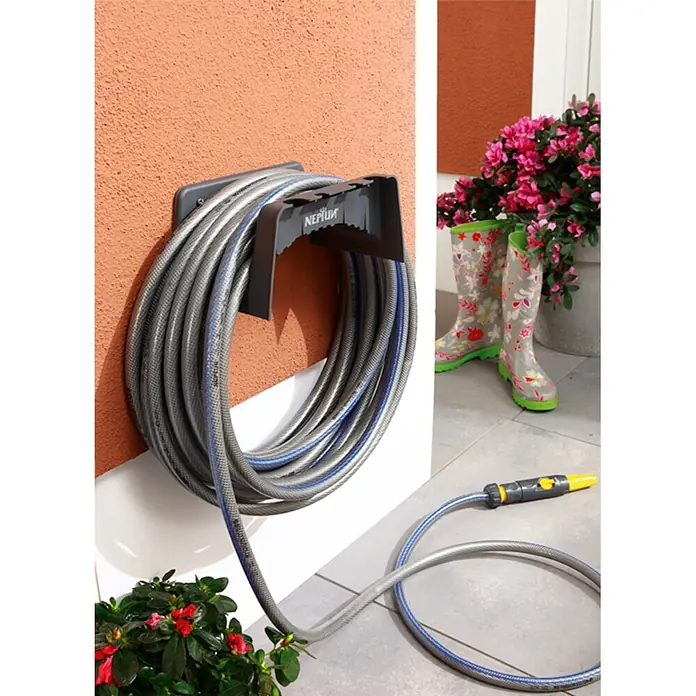 Neptun Wand-Schlauchhalterung - Kunststoff - Eine aufgerollte NEPTUN Gartenschlauch auf einer Halterung an der Wand mit einer Spritzdüse.