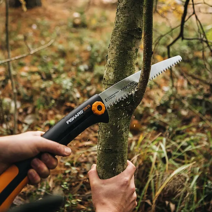 Fiskars Hand-Astsäge Xtract SW75 - Länge: 33 cm, Max. Aststärke: 220 mm, Kunststoff, Orange/Schwarz - Fiskars SW75 Klappsäge mit schwarzem und orangefarbenem Griff sägt einen Baumast im Freien.