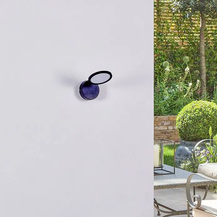 Lindby Deckenstrahler Manel - schwarz, schwarz - Dunkle, runde Wandleuchte mit verstellbarem Kopf, an einer Wand montiert. Sie beleuchtet eine Gartenterrasse.
