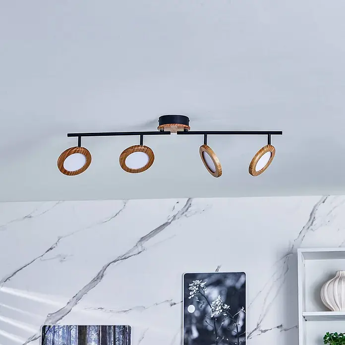 Lindby Deckenstrahler Manel - Holz hell, Holz hell - Schwarze Metallschiene mit vier verstellbaren Strahlern aus Naturholzrahmen und weißen Diffusoren, an der Decke montiert.