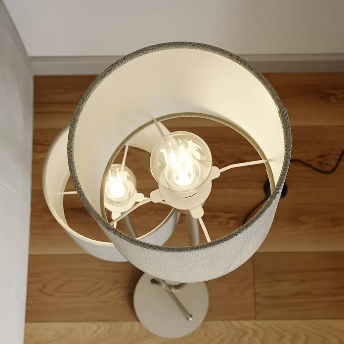 Lucande Stehleuchte Juljana - alu / grau / zink, creme / amber, E14 - Moderne Stehlampe mit zwei beleuchteten, hellen Stoffschirmen und grauem Rand auf Holzboden.