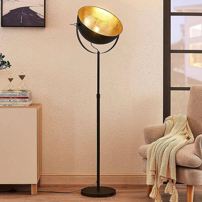 Lindby Stehleuchte Muriel - Höhe: 165 cm, schwarz, schwarz, E27 - Schwarze und goldene Stehleuchte mit schalenförmigem Kopf, beleuchtet eine Wohnzimmerszene.