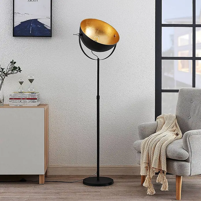 Lindby Stehleuchte Muriel - Höhe: 165 cm, schwarz, schwarz, E27 - Schwarze Stehlampe mit goldener Innenseite, neben einem grauen Sessel in einem Wohnzimmer.