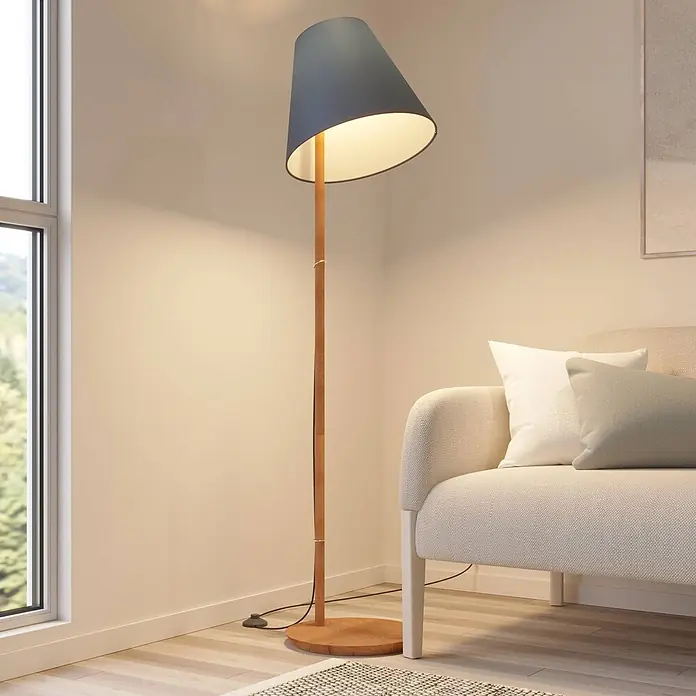 Lucande Stehleuchte Jinda - Holz dunkel, blau, E27 - Eine hohe Stehlampe mit Holzfuß und dunkelblauem konischem Schirm, die eine Wohnzimmerecke neben einem beigen Sofa beleuchtet.