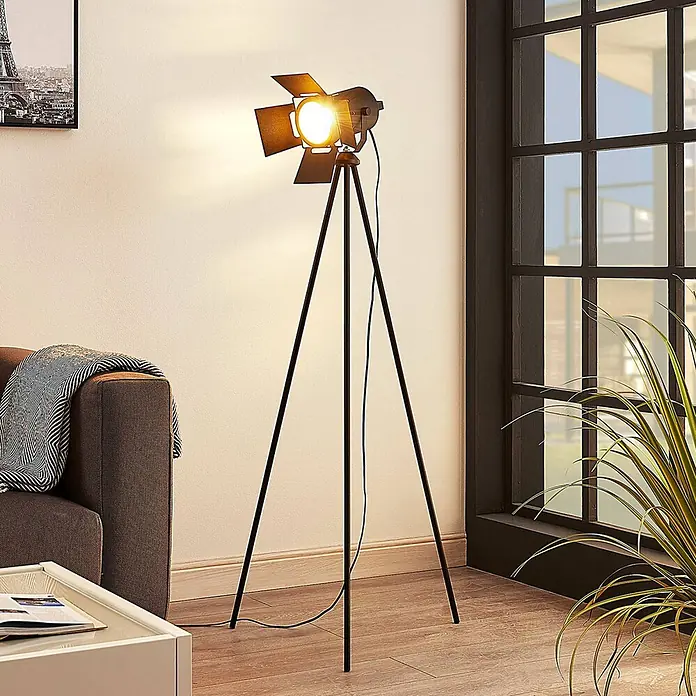 Lindby Stehleuchte Devon - Höhe: 140 cm, schwarz, schwarz, E27 - Schwarze Stehlampe aus Metall auf Stativ mit Scheinwerferkopf, beleuchtet ein modernes Wohnzimmer.
