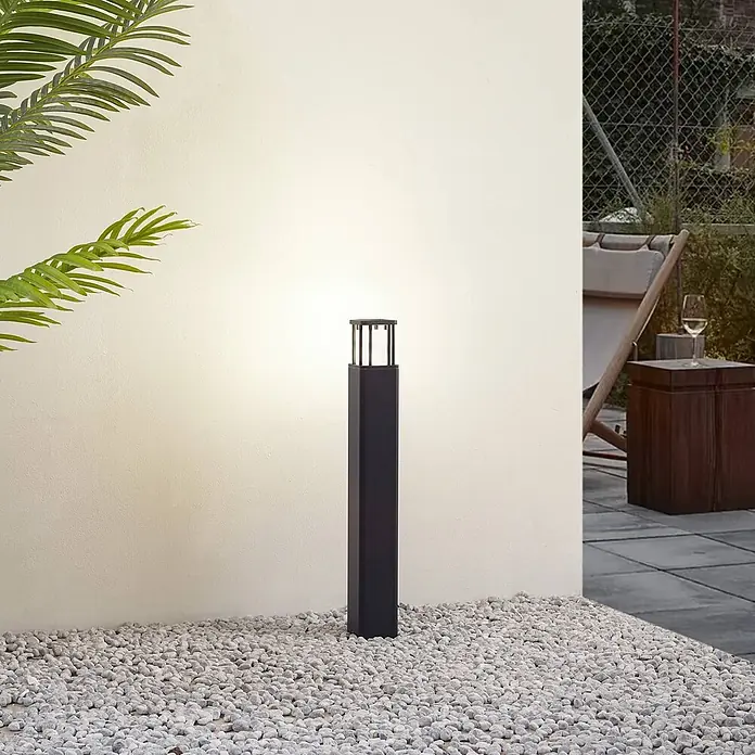 Lucande Außenlaterne Dakil -  - Dunkelgraue, quadratische Außenpollerleuchte beleuchtet Kies und Terrassenbereich.