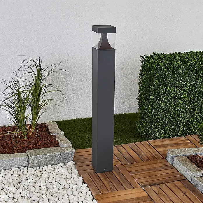 Lucande Außenlaterne Egon -  - Dunkelgraue quadratische Außenpollerleuchte mit transparentem Oberteil in einer Gartenumgebung.