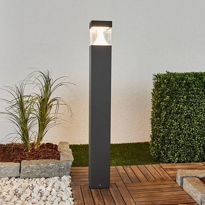 Lucande Außenlaterne Egon -  - Moderne anthrazitfarbene LED-Wegeleuchte mit klarer Oberseite, die einen Gartenweg beleuchtet.