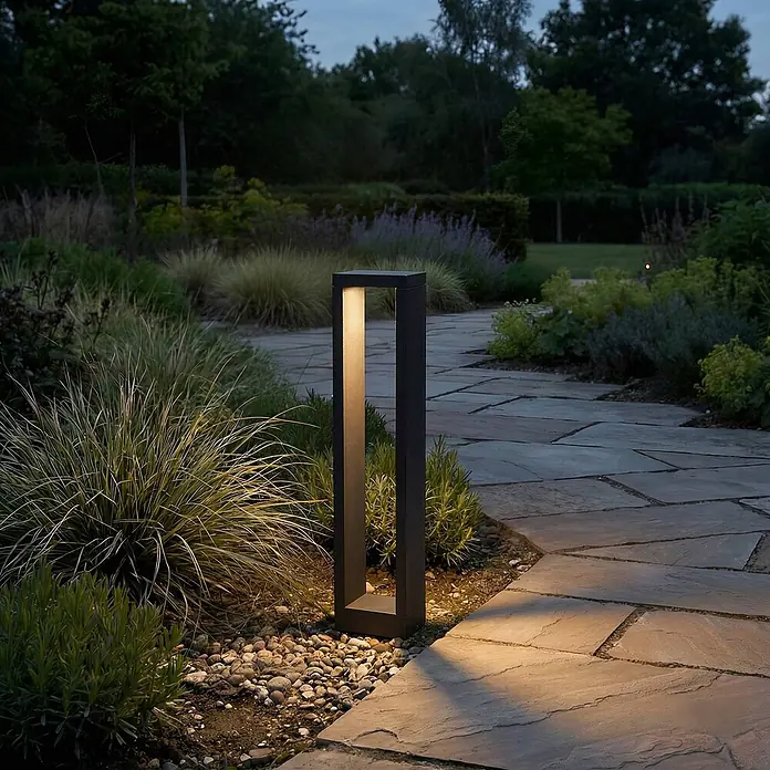 Lucande LED Wegeleuchte anthrazit Sockelleuchte 60 cm Gartenlampe Aluminium -  - Dunkle, moderne rechteckige Außen-Pollerleuchte, die einen Gartenweg im Dämmerlicht beleuchtet, umgeben von Pflanzen.
