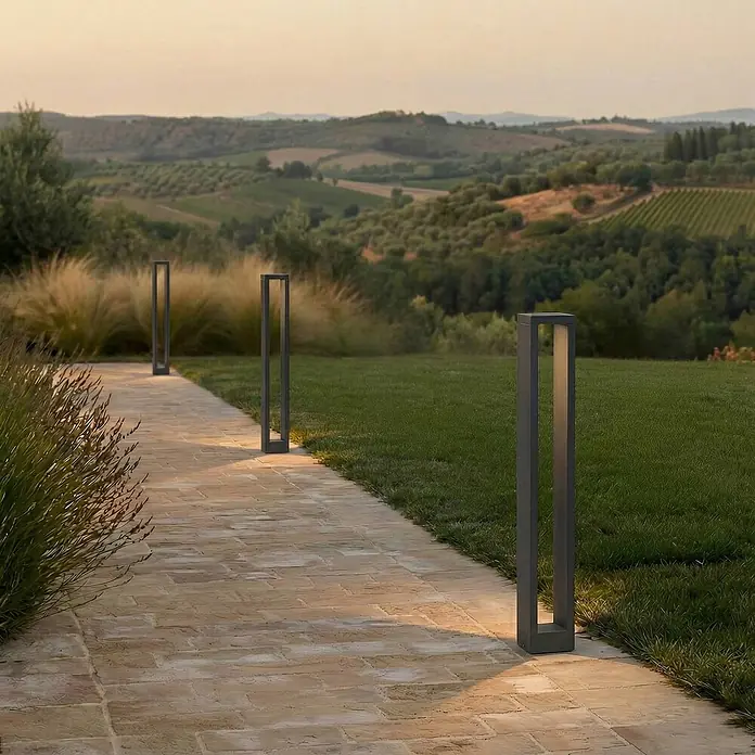 Lucande Außenlaterne Jupp -  - Moderne dunkelgraue rechteckige Pollerleuchten werfen warmes Licht auf einen gepflasterten Gartenweg.