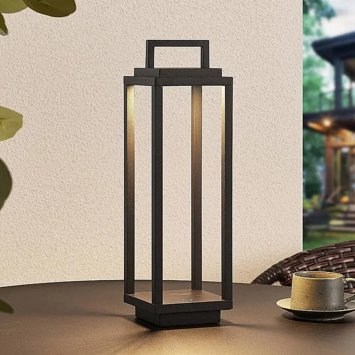 Lucande Außenlaterne Mirina - 10 x 10 x 33,5 cm - Schwarze, rechteckige Laternenlampe mit warmer LED-Beleuchtung auf einem Außentisch neben einer Tasse für Terrassenambiente.