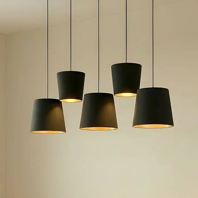 Lucande Pendelleuchte Thamila - schwarz, Schwarz, gold, messing, E27 - Fünf schwarze Pendelleuchten mit warmem Innenschein hängen von einer hellen Decke.