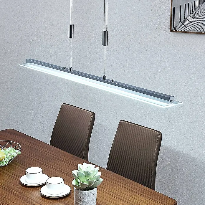 Lindby Pendelleuchte Sladja - L x B x H: 100 x 10 x 4 cm, chrom, satiniert, klar - Moderne silberfarbene lineare Pendelleuchte beleuchtet einen Esstisch aus Holz.