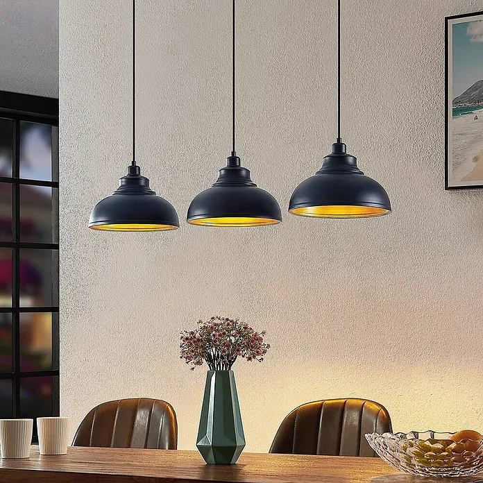 Lindby Pendelleuchte Emna - L x B x H: 101 x 29 x 16 cm, schwarz, Schwarz, gold, E27 - Drei schwarze Pendelleuchten mit goldenem Interieur hängen über einem Esstisch und spenden warmes Licht.