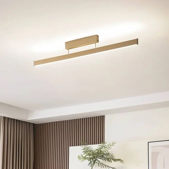 Lucande Deckenleuchte Mylosh - messing / gold - Matte goldene lineare LED-Deckenleuchte, bündig montiert, beleuchtet einen modernen Raum.