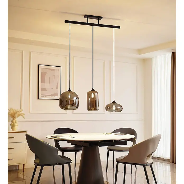 Lindby Pendelleuchte Arloris - alu / grau / zink, rauchgrau, Schwarz, E27 - Drei moderne Pendelleuchten aus Rauchglas mit schwarzer Aufhängung über einem Esstisch.
