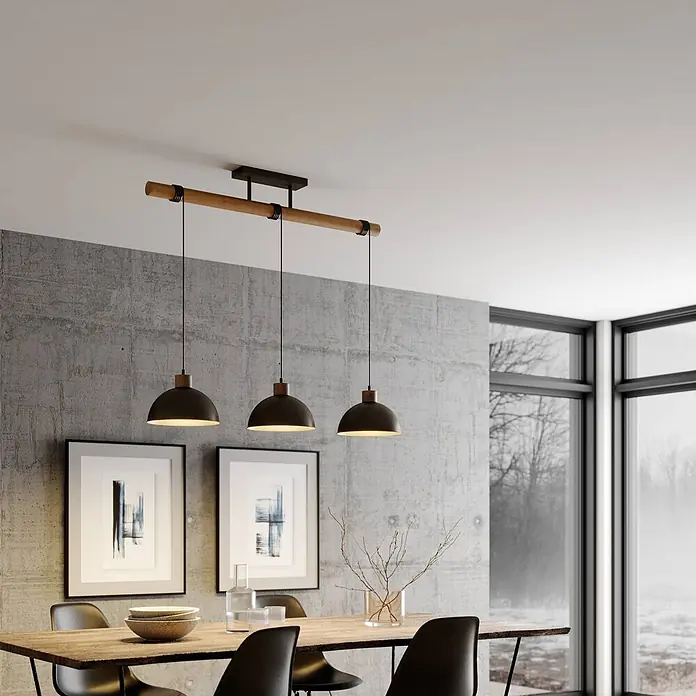 Lindby Pendelleuchte Holgar - L x B x H: 107,5 x 26,5 x 37,5 cm, alu / grau / zink, grau, holz hell, E27 - Lineare Pendelleuchte mit drei schwarzen Metallschirmen und einem Holzbalken über einem Esstisch.
