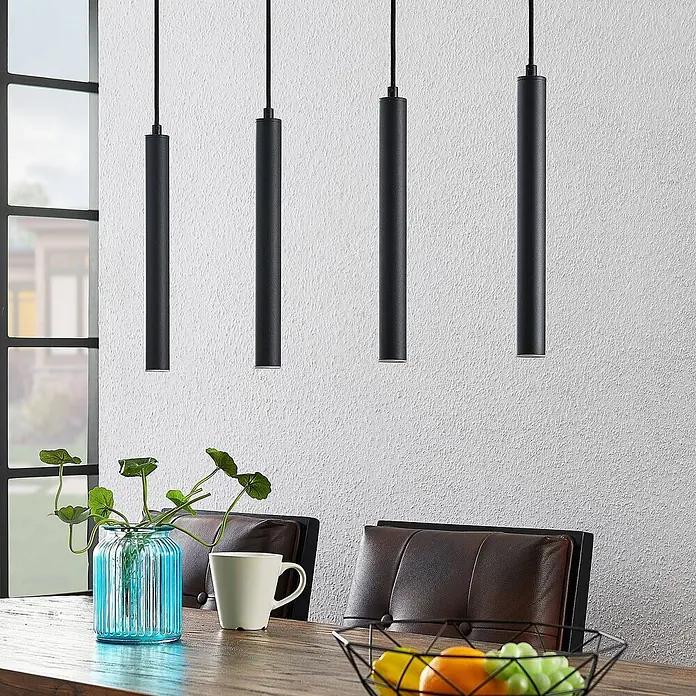 Arcchio Pendelleuchte Kammeron - schwarz, Schwarz - Vier schwarze zylindrische Pendelleuchten hängen über einem Holztisch und beleuchten den Essbereich.