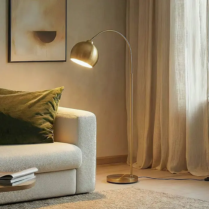 Lindby Stehleuchte Moisia - Höhe: 150 cm, messing / gold, messing / gold, E27 - Eine goldene Bogenstehlampe steht neben einem weißen Sofa und beleuchtet den Raum mit warmem Licht.