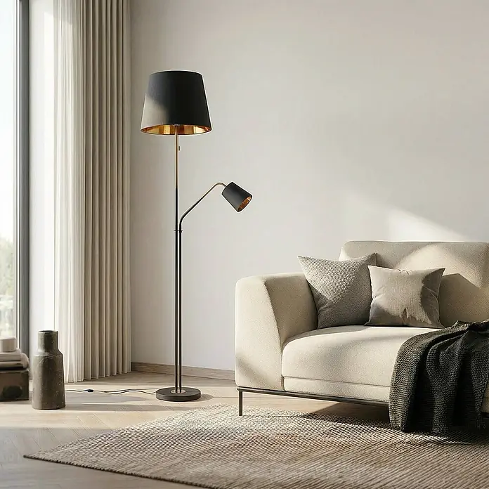 Lindby Stehleuchte Efalia - schwarz, schwarz, E27 - Hohe Stehlampe mit schwarzem und goldenem Hauptschirm und verstellbarer Leselampe, neben einem cremefarbenen Sofa.