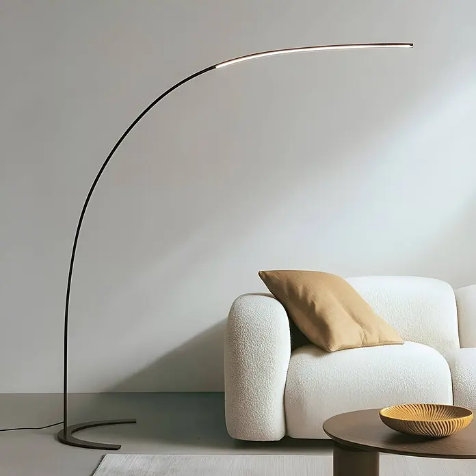 Lindby Stehleuchte Danua - schwarz, schwarz - Schlanke, dunkle Bogenstehlampe mit integriertem linearem LED-Licht, beleuchtet einen modernen Wohnraum mit Sofa.