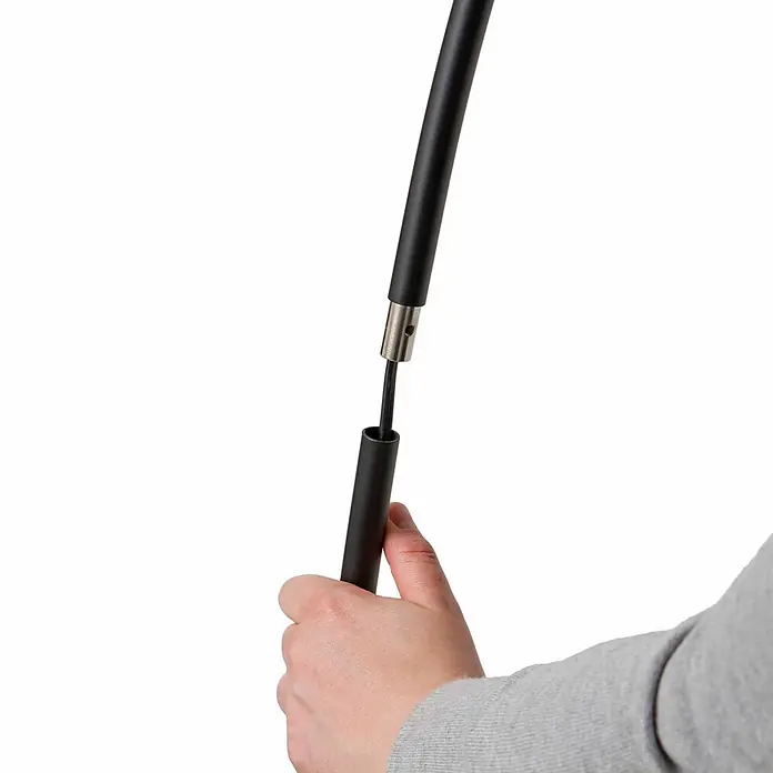 Lindby Stehleuchte Danua - schwarz, schwarz - Zwei schwarze Zeltstangensegmente mit silbernem Verbinder und Gummikordel werden von einer Hand zusammengebaut.
