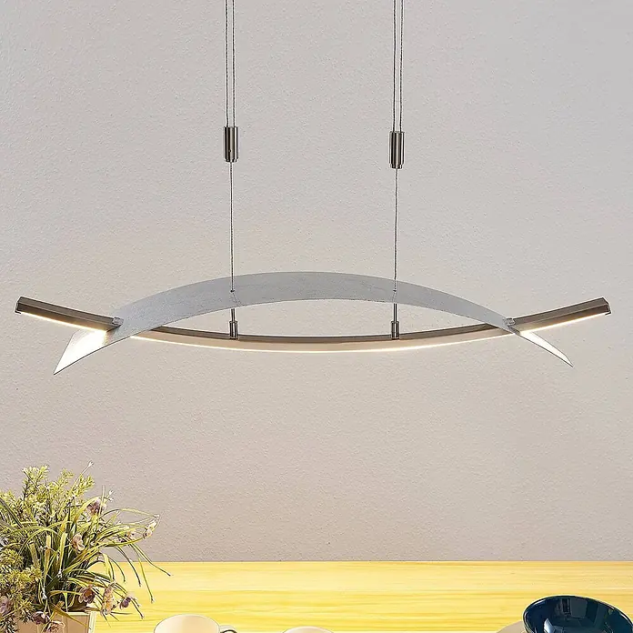 Lucande Pendelleuchte Marija - L x B x H: 90,5 x 20 x 1,8 cm, chrom / silber, silber - Moderne silberne, gebogene LED-Pendelleuchte, die einen Holztisch beleuchtet.