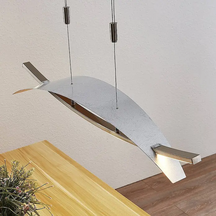 Lucande Pendelleuchte Marija - L x B x H: 90,5 x 20 x 1,8 cm, chrom / silber, silber - Moderne, silberfarbene Hängeleuchte mit wellenförmigem Design, über einem Holztisch hängend und nach unten leuchtend.
