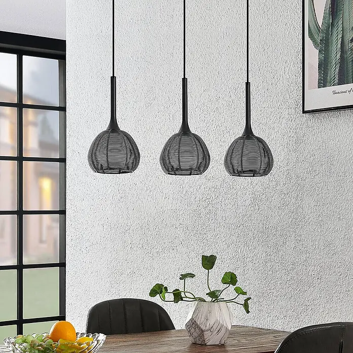 Lucande Pendelleuchte Tetira - schwarz, Schwarz, weiß, E14 - Drei schwarze Pendelleuchten aus Metalldraht hängen über einem Holztisch und beleuchten einen modernen Essbereich.