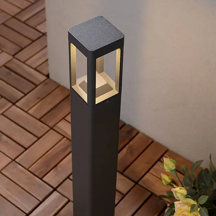 Lucande Außenlaterne Bernd -  - Quadratische dunkelgraue Außenleuchte beleuchtet eine Holzterrasse mit warmem gelbem Licht.