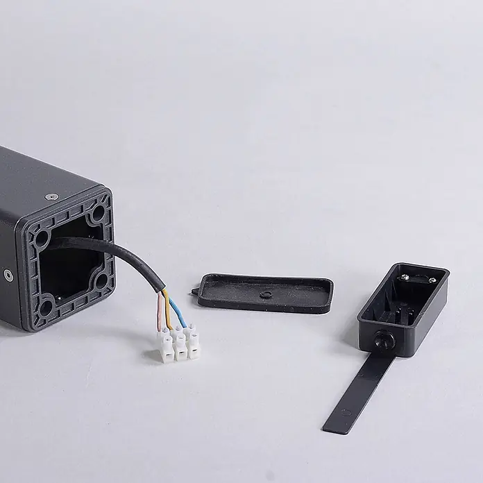 Lucande Außenlaterne Bernd -  - Dunkelgraues Elektrogehäuse mit Kabel und weißem Klemmenblock. Daneben eine schwarze Klemmenbox und deren Abdeckung.