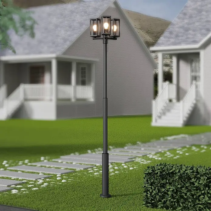 Lucande Außenlaterne Siveta -  - Eine schwarze Dreifach-Laterne beleuchtet einen Gartenweg vor Häusern.