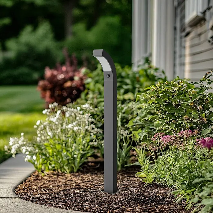 Lucande Außenlaterne Lennik - 20 x 12 x 100 cm - Anthrazitfarbene Außenleuchte mit gebogenem Design und Sensor, in einem Gartenweg installiert.