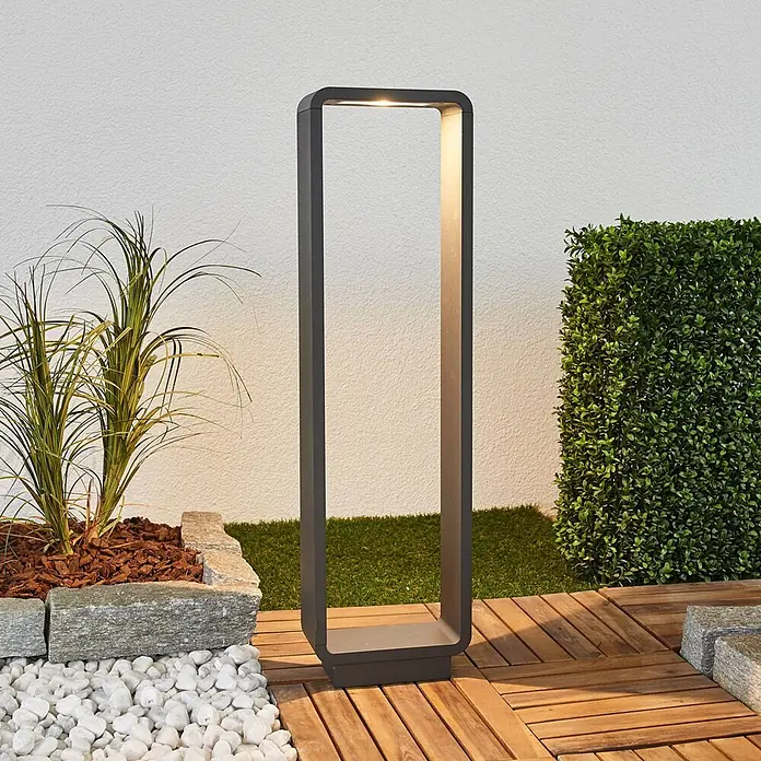Lucande Außenlaterne ninon -  - Dunkelgraue, rechteckige Pollerleuchte für den Außenbereich mit beleuchtetem Rahmen, auf Holzterrasse im Garten stehend.