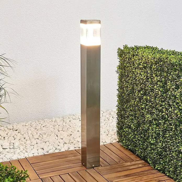 Lindby LED Wegeleuchte in edelstahl, transparent, Gartenlampe -  - Außenpollerleuchte aus Edelstahl mit beleuchteter Oberseite, auf Holzdeck und weißen Kieselsteinen.