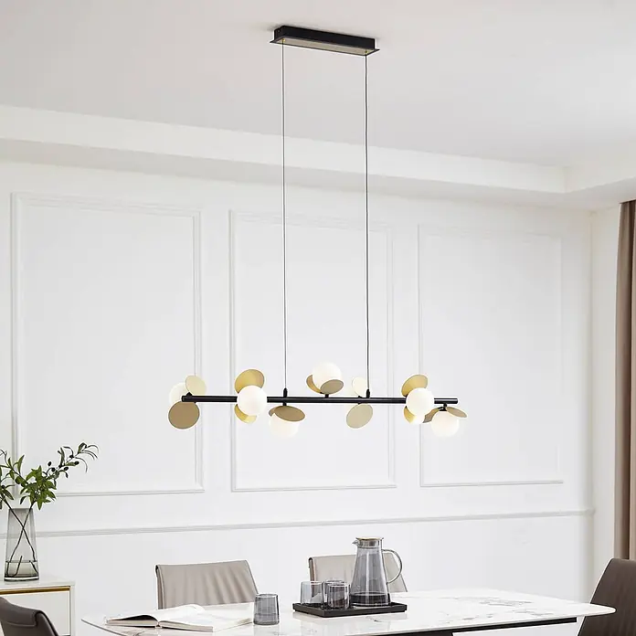 Lucande Pendelleuchte Pallo - L x B x H: 100 x 23,5 x 18 cm, Schwarz, gold, weiß - Moderne schwarze und goldene Pendelleuchte mit weißen Kugelgläsern, über einem Esstisch in einem hellen Raum hängend.