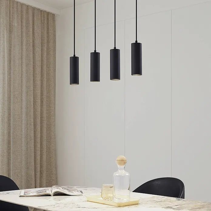 Lindby Pendelleuchte Joffrey - L x B x H: 76 x 6 x 18 cm, schwarz, Schwarz, GU10 - Vier schwarze zylindrische Pendelleuchten hängen über einem Esstisch in einem modernen Interieur.
