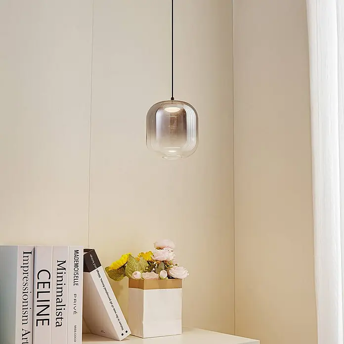 Lucande Pendelleuchte Avelinra - L x B x H: 14 x 14 x 17 cm, alu / grau / zink, rauchgrau, Schwarz - Eine Pendelleuchte aus Rauchglas hängt an einem schwarzen Kabel und beleuchtet ein modernes Interieur.