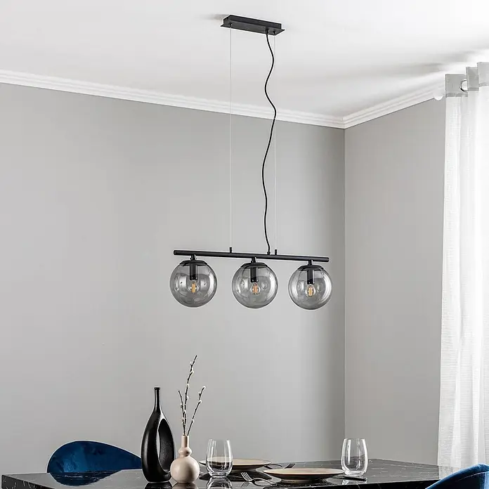 Lucande Pendelleuchte Sotiana - alu / grau / zink, rauchgrau, Schwarz, E14 - Schwarze Pendelleuchte mit drei Rauchglas-Kugeln über einem modernen Esstisch.