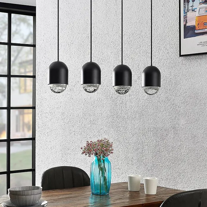 Lucande Pendelleuchte Amielle - L x B x H: 71 x 11 x 17 cm, schwarz, Schwarz, klar, GU10 - Vier schwarze Pendelleuchten mit klaren, strukturierten Glaselementen beleuchten einen Esstisch.